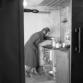 Perheen äiti hellan ääressä kellarissa sijaitsevassa asunnossa. 1956