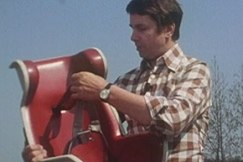 Kuva: Mies esittelee autoon tarkoitettua lasten turvaistuinta. YLE kuvanauha.