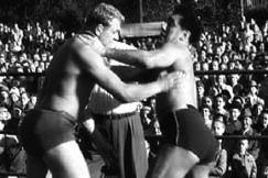 Kuva: Amerikkalaiset vapaapainijat toistensa kurkussa Linnanm�ell� vuonna 1953. YLE kuvanauha.