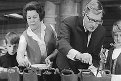 Kuva: �iti ja is� opettajat lapsilleen hyvi� k�yt�stapoja seisovanp�yd�n ��rell�. YLE kuvanauha. 