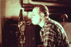 Kuva: Lasinpuhaltaja ottaa lasimassasta tulta savukkeeseen. (1956) YLE kuvanauha.
