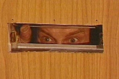 Kuva: Mies (Paavo Piskonen) katsoo postiluukusta. Ulosmittaajat (1982). YLE kuvanauha.