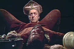 Kuva: Piispa Henrik (Olavi Ahonen) katsoo Lallin (Markku Blomqvist) jalkojen v�list�. YLE kuvanauha. 