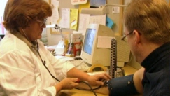 Kuva: Terveydenhoitaja Heli Isola mittaa verenpainetta toimittaja Jyrki Vuorelta (1998) Yle kuvanauha